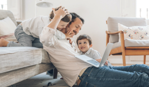 Father using laptop with two young sons