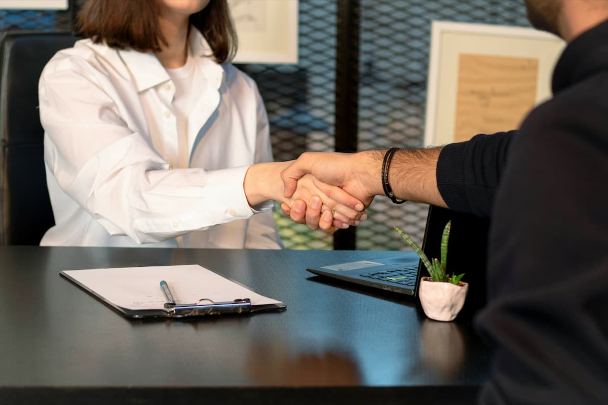 Two people are shaking hands across a desk.